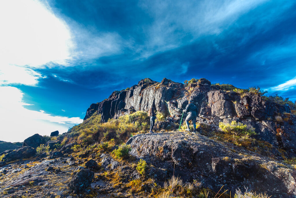 Pareja de excursionistas caminando hacia la cima de una montaña en medio del páramo en el Parque Nacional Chirripó en Costa Rica