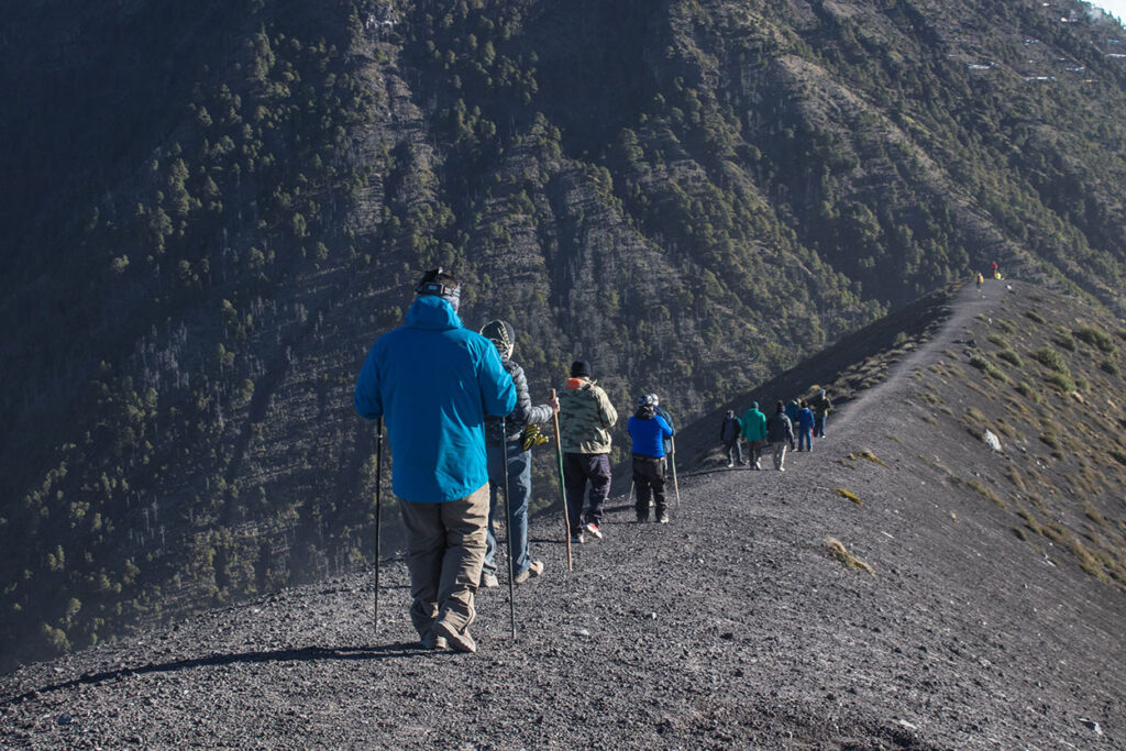 Senderista caminando por el camellón del Volcán de Fuego con vista al campamento Acatenango, Guatemala