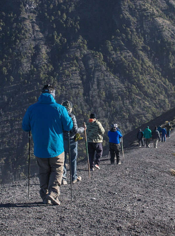 Senderista caminando por el camellón del Volcán de Fuego con vista al campamento Acatenango, Guatemala